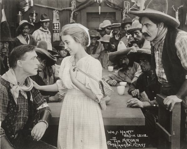 The leader of a band of Mexican desperadoes, Steve Denton (played by William S. Hart), has his heart softened by the innocent young Mary Beth Garth (Bessie Love) in this scene still for the silent western "The Aryan." The outlaw in the right foreground is probably Mexican Pete, played by Ernest Swallow.