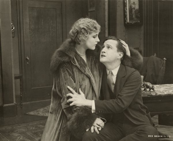 Lorelei Knight (played by Rubye de Remer) embraces Bob Wharton (Tom Powers) in a scene still for the melodrama "The Auction Block." She wears a fur coat and pearls.
