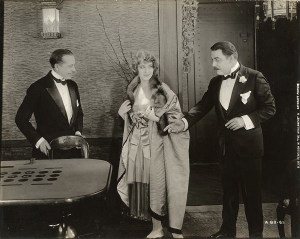 A card dealer watches as Nick Delano (played by Warner Oland) shows Helene (Elsie Ferguson) to the gambling table in a scene still from the 1919 Famous Players—Lasky drama "The Avalanche."