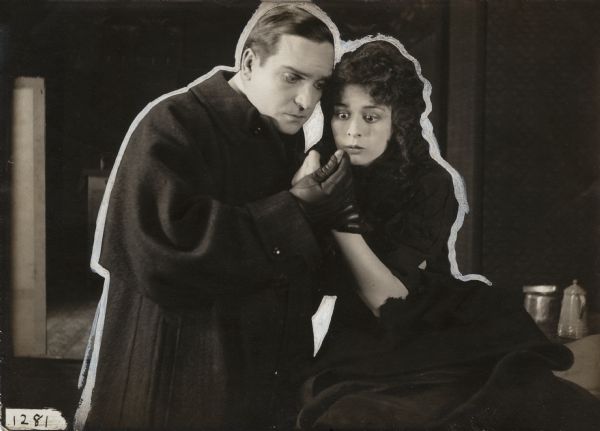 Roscoe Thane (played by Earle Williams) and Jo, a girl of the slums (played by Anita Stewart), closely examine the thumb of Jo's left hand in a scene still for "The Awakening" (Vitagraph 1915).