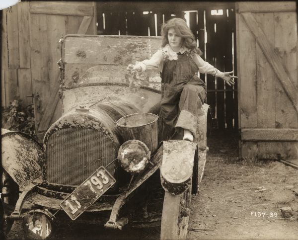 Bab Archibald (played by Marguerite Clark) washes a very muddy automobile that appears to be an Overland open touring car in this scene still for "Bab's Burglar."