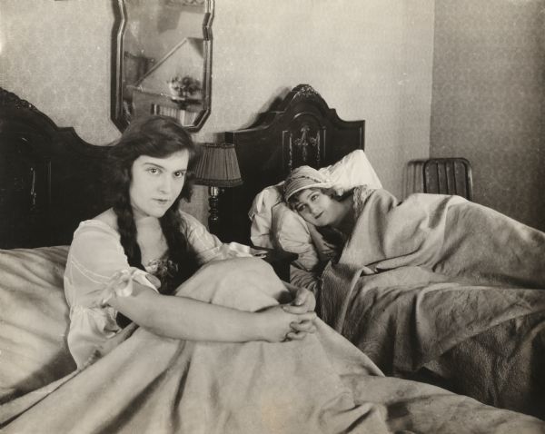 Dressed in their nightgowns, Zoie (played by Madge Kennedy) and Aggie (Kathryn Adams) are in twin beds. Kennedy is sitting up and Adams is lying down.