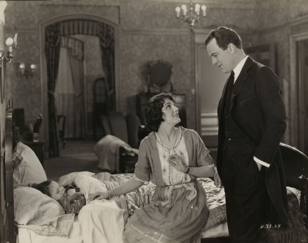 Tucked in bed, the orphaned baby Toodles (played by Bruce Guerin) is attended by Sally Lockwood (Leatrice Joy) who is the secretary of Richard Chester (Thomas Meighan) in a scene still for the 1922 silent drama "The Bachelor Daddy."