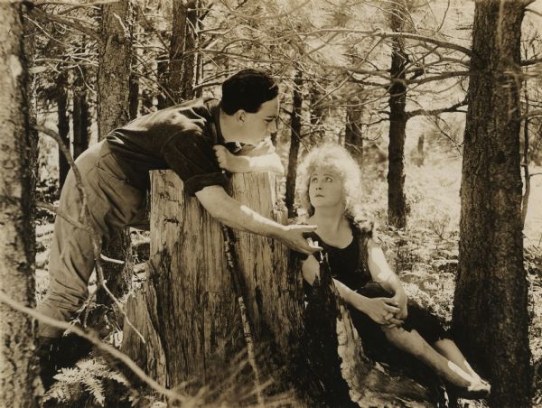 In a scene still for "Bawbs o' Blue Ridge," Ralph Gunter (played by Arthur Shirley) talks to Barbara "Bawbs" Colby (Bessie Barriscale) in a forest of the Appalachian Mountains.