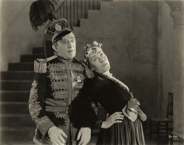 Dr. Arbutus Budd (played by Raymond Hitchcock in an aristocratic uniform) appears stunned as Cremo Panatella (Louise Fazenda made up with a large false nose) flirts with him in a scene still for the 1922 comedy "The Beauty Shop."