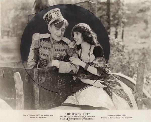 Raymond Hitchcock (in costume as Dr. Arbutus Budd pretending to be an Italian noble) and Marion Fairbanks (as Cola, an Italian girl) grin at each other in a heavily retouched publicity still for the 1922 comedy "The Beauty Shop."