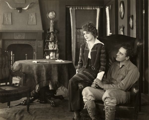 An aspiring actress, Dolly Lane (played by Mary Pickford) longs for the stage but feels trapped on the farm of her husband Steve Hunter (played by James Kirkwood). In their farmhouse parlor, she sits on the arm of the wing back chair he is sitting in. Besides playing Steve Hunter, Kirkwood was also the director of "Behind the Scenes," a silent drama from 1914.