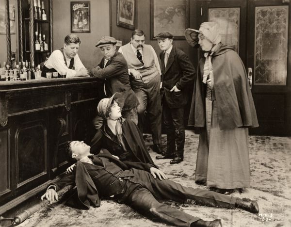 Jack Bronson (played by Raymond Bloomer) has been beaten senseless in an underworld bar. Violet Gray (played by Marion Davies dressed in a Salvation Army uniform) kneels beside him to offer aid in a scene still from the silent drama "The Belle of New York."