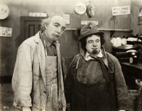 Hardware store owners Louie Vanderiff (played by Clarence Kolb at left) and Mike Amsterdammer (Max Dill) pose in rough working clothes in a scene still for the 1917 silent comedy "Beloved Rogues." Kolb and Dill were a "Dutch act" vaudeville team similar to the more famous pair Weber and Fields.