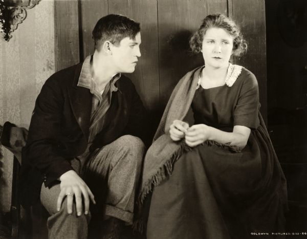 Chester Morris and Mae Marsh are seated and looking worried in this scene still for the 1918 Goldwyn silent drama "The Beloved Traitor."