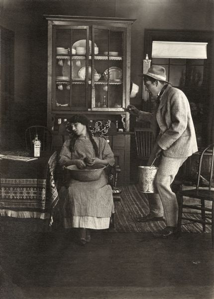 The farm's hired hand John (played by Owen Moore) carefully approaches Betty the cook (Florence Lawrence) who has fallen asleep while peeling a potato in a scene still for the silent comedy "Betty's Nightmare." On the table next to her is the book "Acting Made Easy" and a bottle of Indian Cure-All patent medicine.