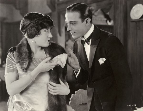 Theodora Fitzgerald (played by Gloria Swanson) looks into the eyes of Lord Hector Bracondale (Rudolph Valentino) who is returning her handkerchief in a scene still from the silent drama "Beyond the Rocks." Swanson wears a fox stole.