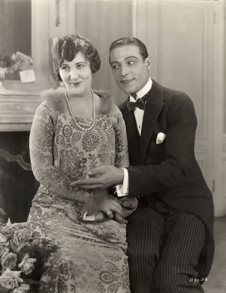 Mabel Van Buren (as Mrs. McBride) and Rudolf Valentino (Lord Hector Bracondale) sit side by side in a scene still for the silent drama "Beyond the Rocks."