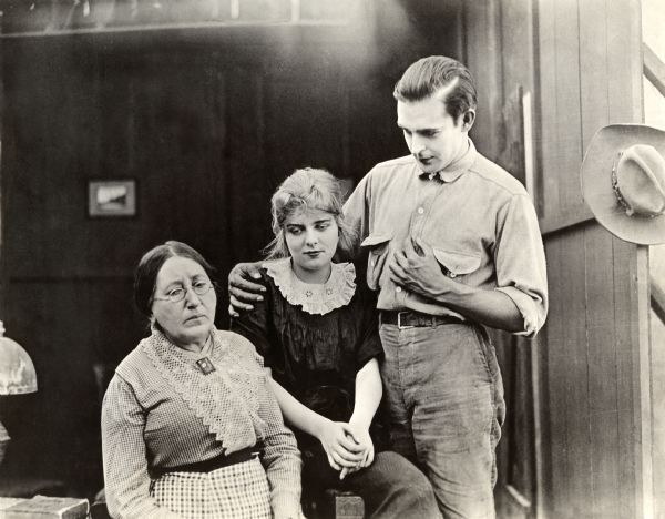 Josephine Crowell, Blanche Sweet, and Wallace Reid are in a scene still set in a rural interior, probably for a Majestic Motion Picture silent drama of 1914.