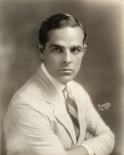 Head and shoulders studio publicity portrait of silent film star Antonio Moreno in a light-colored suit and striped necktie.