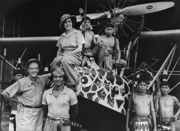 Osa Johnson, Martin Johnson, and Murut people pose with the Johnson's Sikorsky S-39 "The Spirit of Africa and Borneo" in a publicity still for the 1937 motion picture "Borneo."