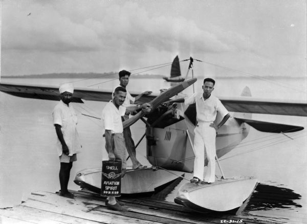 Dr. Johann “Val” Stokes (holding fuel can) and his Aeronca C-3 float plane, Sandakan Harbor, Borneo.