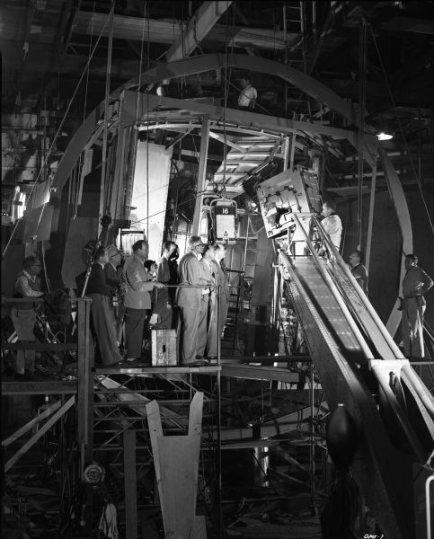 Executives and crew for the 1950 science fiction film "Destination Moon" look into the rotatable space ship interior set. The tall, white-haired man in glasses is the director Irving Pichel. Directly in front of him is the producer George Pal. A huge blimped Technicolor motion picture camera is mounted on a crane.