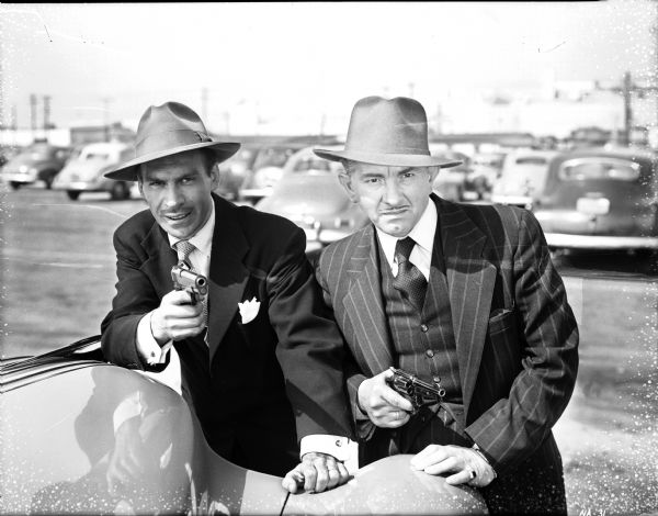 Two men with drawn pistols in a parking lot in a scene still for "Federal Man."