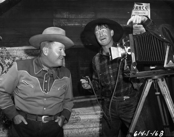 Actors Jack Oakie (left) and Victor Killian (pointing to the camera) use an 8x10 inch field camera as a prop in a publicity still for the 1948 western "Northwest Stampede."