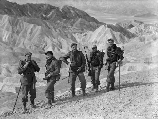 The crew of Rocketship X-M survey the rugged terrain of Mars. From left to right they are played by John Emery, Osa Massen, Lloyd Bridges, Noah Beery Jr., and Hugh O'Brian.