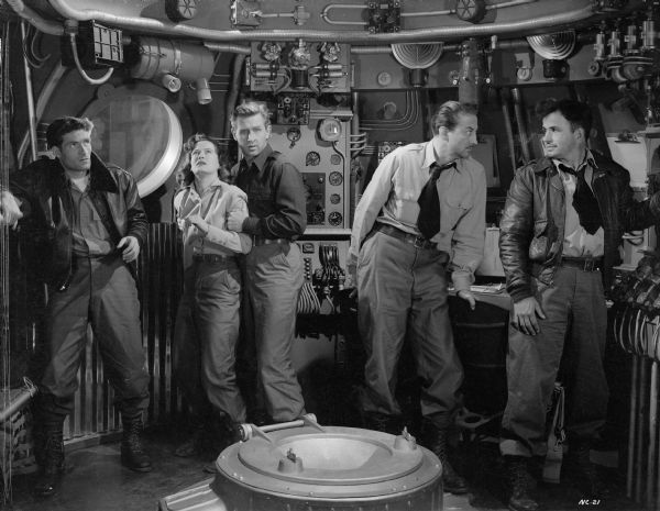 The crew looks tense in a scene still from the 1950 science fiction film "Rocketship X-M." From left to right the actors are Hugh O'Brian, Osa Massen, Lloyd Bridges, John Emery, and Noah Beery Jr.