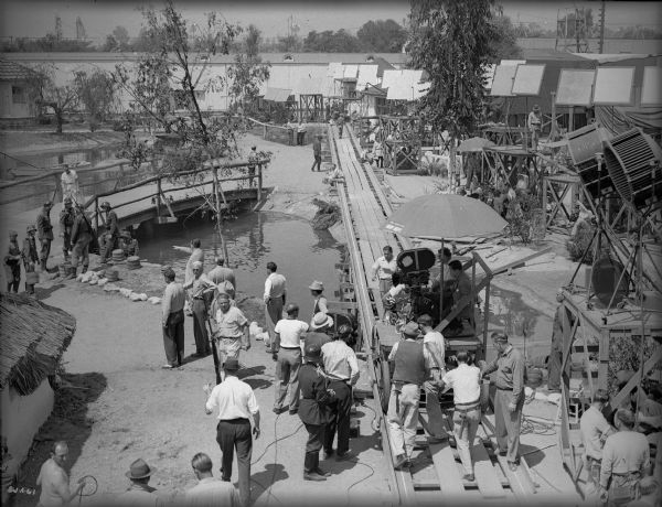The crew and cast of "The North Star" prepare to shoot a tracking shot of the Ukrainian village set built on the Samuel Goldwyn Studios lot. James Wong Howe, the cinematographer sits on the left side of the camera.