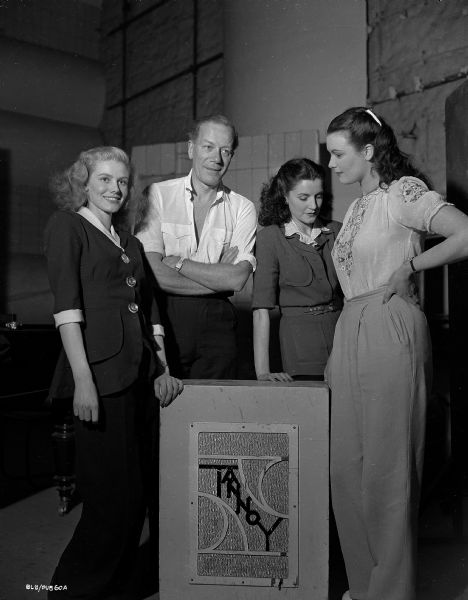 Actor Cyril Ritchard and three young women, presumably from the cast of "The Winslow Boy," listen to the Tannoy public address system.