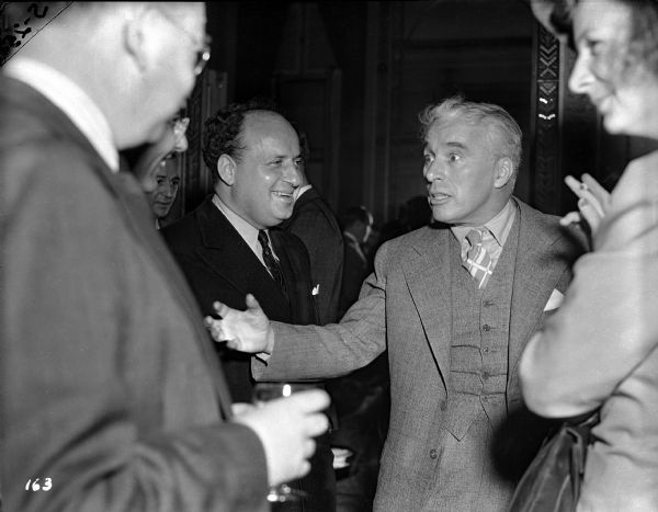 Charlie Chaplin entertains the press at a press conference held at the Waldorf-Astoria in New York on October 13, 1940, to promote "The Great Dictator." United Artists executive Maurice Silverstone stands beside Chaplin on the left.