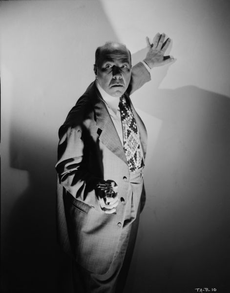 Ben Welden, playing the gangster Sniffy, poses with his revolver in hand in a dramatic publicity still for "Tough Assignment."