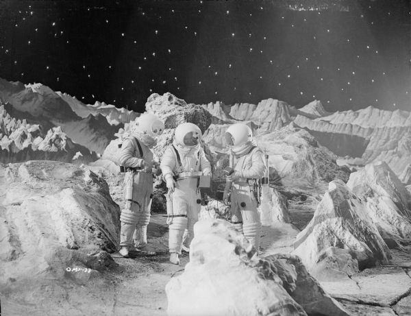 Three space suited astronauts stand on the lunar surface against a background of stars in a scene still for "Destination Moon."