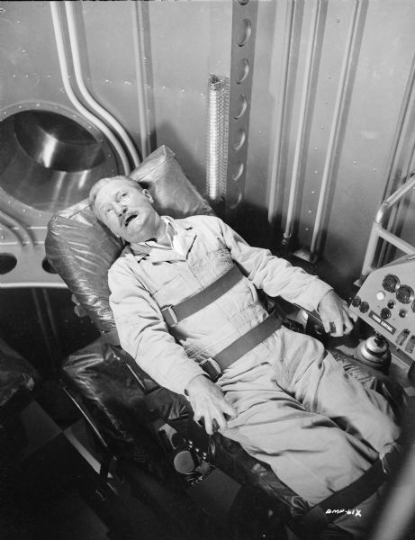 Actor Tom Powers shows signs of distress strapped onto a spaceship bunk in a publicity still for "Destination Moon."
