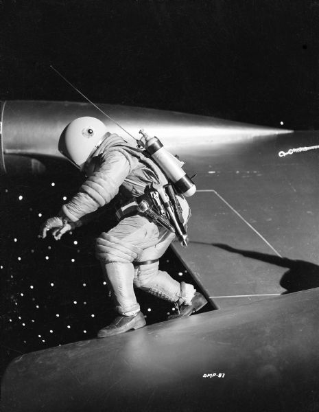 An astronaut walking along the hull of a spaceship has become unclipped from his safety rope in a publicity still for "Destination Moon."
