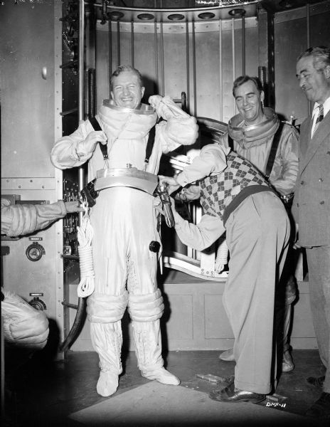 Actor Tom Powers is being dressed in an astronaut costume for "Destination Moon." On the right are Warner Anderson, already in costume, and the director Irving Pichel.