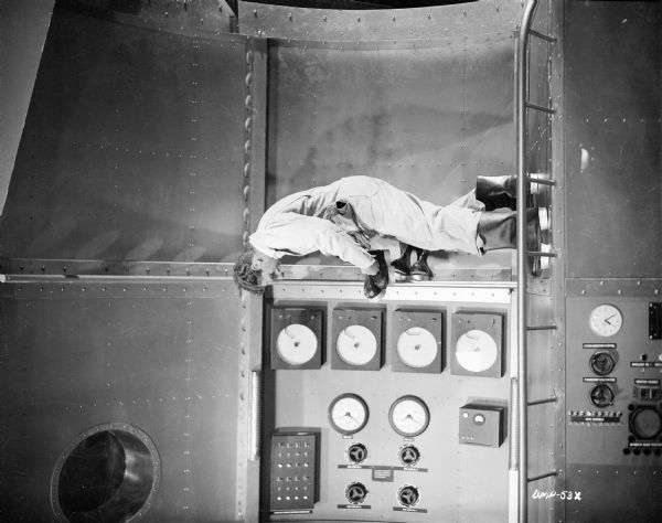 John Archer, wearing suction boots, walks down a wall of a spaceship interior in a scene still for "Destination Moon."