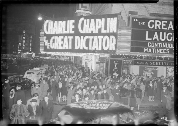 Crowds gathering under the marquee of the Capitol Theatre for the New York premiere of Charlie Chaplin's "The Great Dictator" the evening of October 15, 1940. The sign for the Rivoli Theatre can be seen further down Broadway.