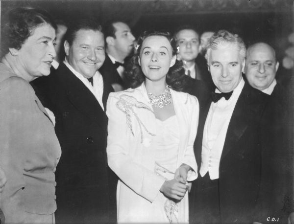 From left to right, Constance Collier, Jack Oakie, Paulette Goddard, and Charlie Chaplin stand in the crowed lobby of New York's Capitol Theater for the premier of "The Great Dictator," October 15, 1940.