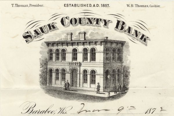 Memohead of the Sauk County Bank of Baraboo, Wisconsin, established in 1857, with a three-quarter view of the bank building and people walking on the sidewalk.