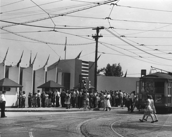 View from road of crowd of people walking towards the entrance to the Wisconsin Centennial Exposition on Greenfield Avenue.