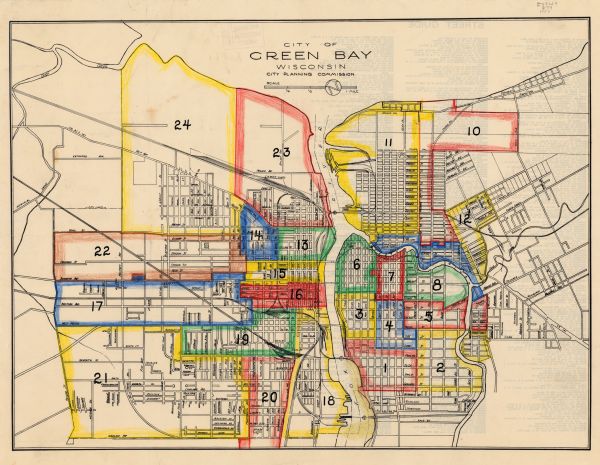 This map shows streets and railroads and is oriented with north to the upper left. Wards have been outlined in yellow, red, blue, and green. The back of the map features a street guide. 
	