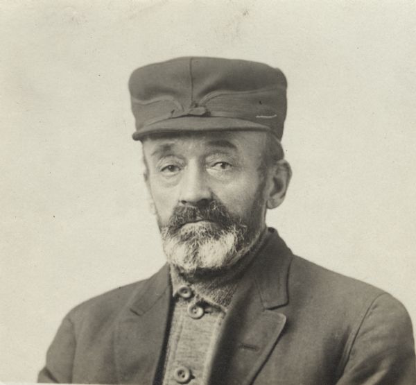 Quarter-length portrait of unidentified man with a beard and moustache, wearing a shirt, jacket and hat (Stormy Kromer).