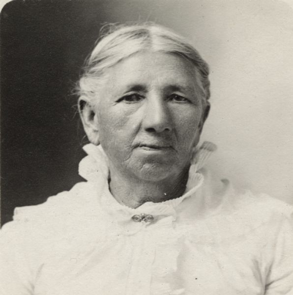 Quarter-length portrait of unidentified woman wearing a light-colored dress with a ruffled collar and a pin.