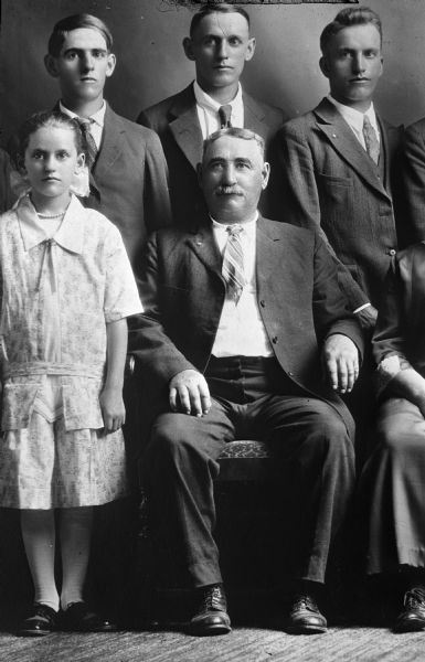 Copy of a family portrait that includes a father, daughter and three sons. Two people on the right are only partially visible.