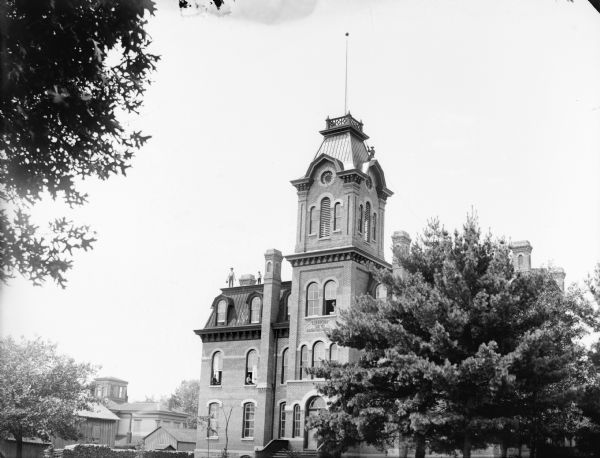 Union High School, constructed in 1871. It later probably became a grade school. Men, perhaps workmen, are sitting in the second and third floor windows, and other men are standing on the roof.