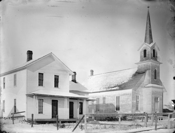 Frame house and church surrounded by snow-covered ground, probably in Hixton. First built in 1877 as a Congregational Church, it cost $2000. It later became a Presbyterian Church and then a Methodist Church.