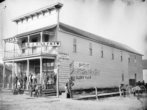 Group portrait of men and boys posing in front of the M.J. Chapman Store, probably in Alma Center, and known contemporarily as the C.T. Gansel Building.	