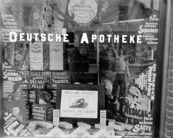Window of the Werner Drugstore with a display for Dr. Pierce's Medicines and a sign that says, "Deutsche Apotheke."	