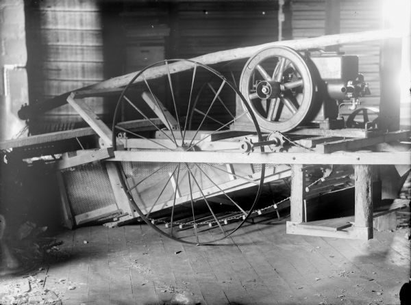 Piece of farm machinery on a wooden floor in a building.