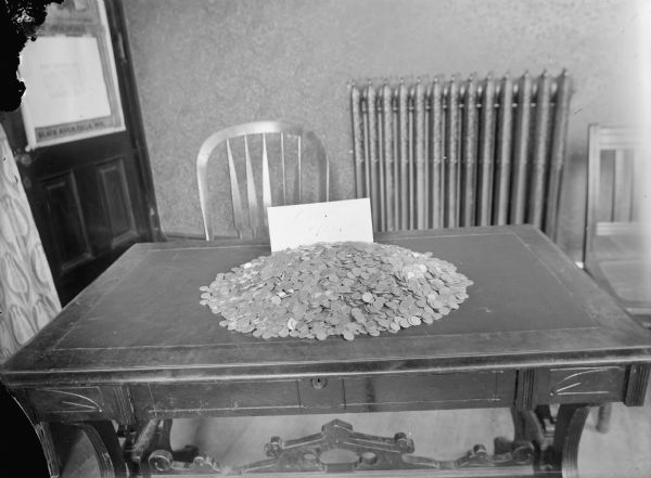 Pile of dimes on a desk with a sign that reads: "Over $1000.00."