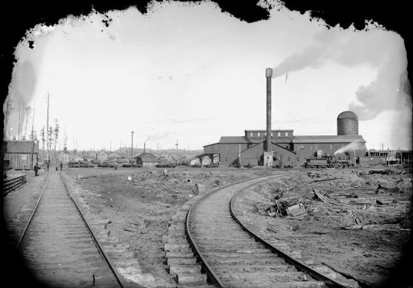 Lumberyard with railroad lines and a sawmill, probably the Goodyear Mill, three miles south of Saddle, or a mill located in McKenna.